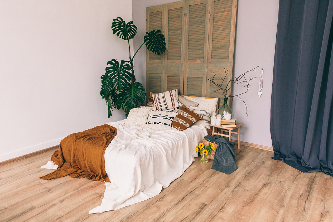 Bed with blankets and pillows in a bedroom. Interior of the room. Plants in room. Loft